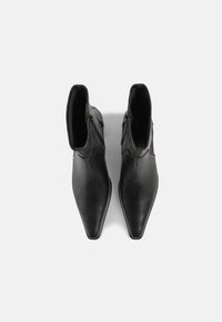 Botoșei de piele negri până la gleznă, cu vârf ascuțit, textură netedă, fermoare laterale și cusături minime. Design elegant și aerodinamic.