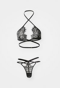Sort blondelingeri-sæt med en trekantet bralette med krydsede stropper og en matchende tanga med et blomstermønster i blondestof.
