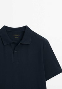 Polo-shirt marine en tissu texturé, avec un col classique et une patte de boutonnage à deux boutons, présenté de l'angle supérieur gauche.
