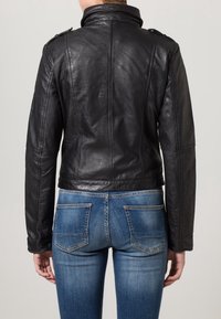 Black leather jacket with a tailored fit, featuring a high collar, shoulder epaulettes, and stitched detailing. Worn over blue denim jeans.