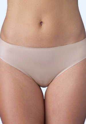 Zbliżenie na środkową część ciała osoby w beżowej bezszwowej bieliźnie na jednolitym jasnym tle.