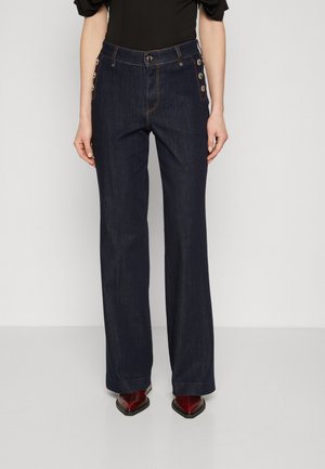 Pantaloni a gamba larga in denim scuro con vita alta, caratterizzati da cuciture arancioni a contrasto e bottoni decorativi sulle tasche laterali.