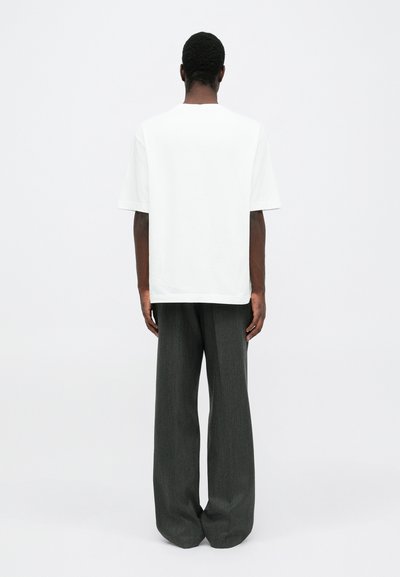 White oversized t-shirt with short sleeves, paired with gray wide-leg pants. Smooth fabric and simple design, showing the back view.