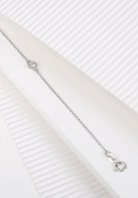 Sterling zilveren kettingarmband met een rond, helder steentje in het midden, met een karabijnsluiting en een delicate, gestructureerde uitstraling.