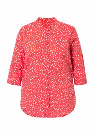 Rød skjorte med knapper, hvide polkaprikker, kvartlange ærmer og en rundet krave, vist på en ensfarvet baggrund.