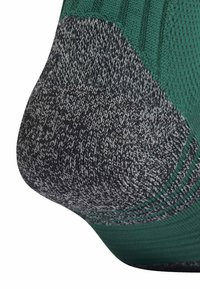 Calcetín de punto con parte superior verde y talón gris texturizado. El talón presenta un tejido con patrón y un diseño reforzado para mayor durabilidad.