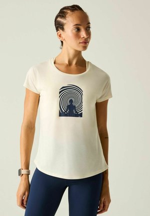 Woman with braided hair wearing a white t-shirt with a black meditating figure and spiral design, and navy leggings, looking sideways.