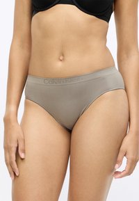 Bežové bezšvové nohavičky Calvin Klein s elastickým pásom, s hladkou textúrou a minimalistickým dizajnom. Žiadne viditeľné vzory ani detaily.