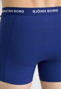 Nærbilde av en person som har på seg tettsittende blå Björn Borg boxershorts med logo på midjebåndet.