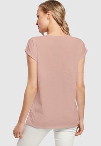 Rožinė trumpa rankovė t-shirt su laisvu kirpimu, pagaminta iš lengvo audinio. Yra sukurtas su apvilluotais rankovėmis ir išlenktu apačia, suteikiančiu neformalią išvaizdą.