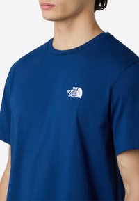 Modrá bavlněná tričko s kulatým výstřihem a krátkými rukávy. Na levé straně hrudi se nachází bílé logo "The North Face."
