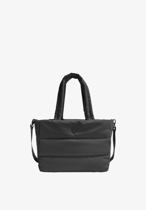 Sac cabas noir matelassé avec deux poignées, une bandoulière amovible et un petit logo en forme de bouclier centré sur le devant.