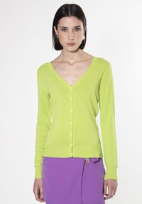 Cardigan verde lime con scollo a V, maniche lunghe e chiusura con bottoni, realizzato in materiale morbido e leggero. Texture liscia, design aderente.