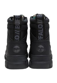 Botines negros con un exterior de cuero suave, suela de goma texturizada y forro de tela. Presenta un logo prominente y lengüetas de tirón.