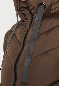 Brown padded jacket with a high collar, featuring gray zipper and drawstrings. The texture is smooth with quilted detailing.