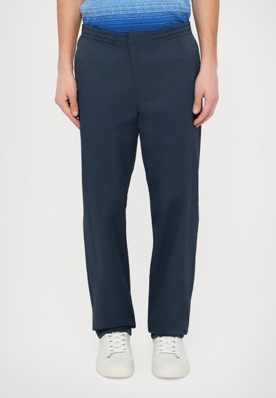 Pantalon bleu marine avec une taille élastique, coupe droite et tissu léger. Assorti à des baskets blanches pour le contraste.