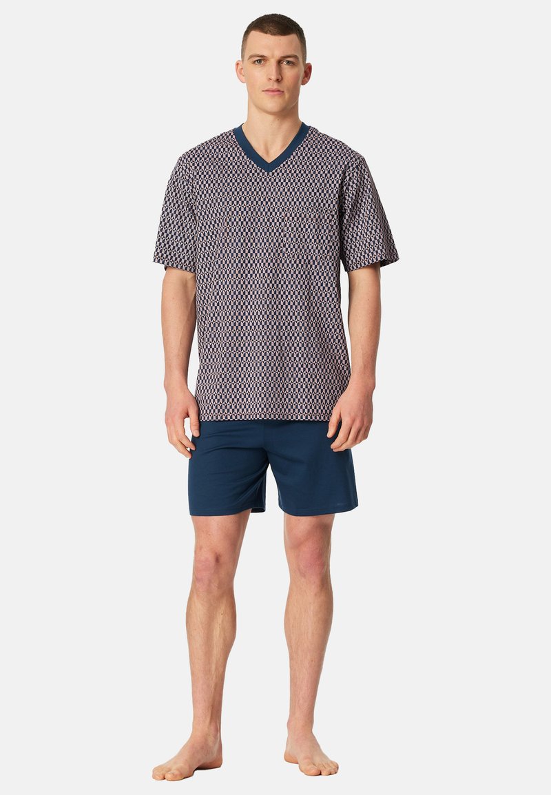 Haut à manches courtes avec motif géométrique bleu marine et blanc, col en V, associé à un short uni bleu marine. Le tissu semble doux et respirant.