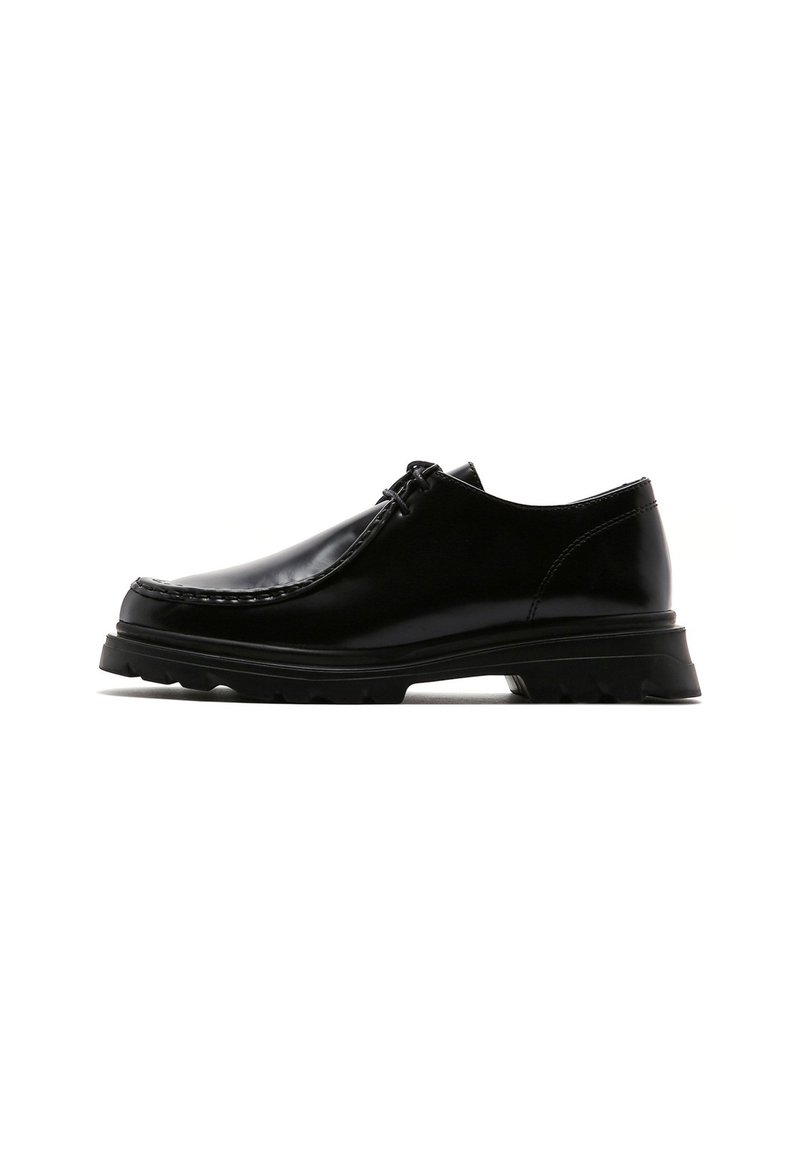 Scarpa elegante in pelle nera con una superficie liscia, punta tondeggiante, design con lacci e suola robusta per trazione.