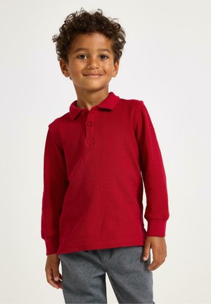 Long-sleeve red polo shirt with a collar, two buttons, and textured fabric, paired with gray patterned trousers.