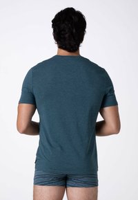 T-shirt in cotone verde acqua con maniche corte e collo rotondo, abbinato a pantaloni corti blu a righe. Vista dal retro, che mostra il colore solido e la vestibilità.