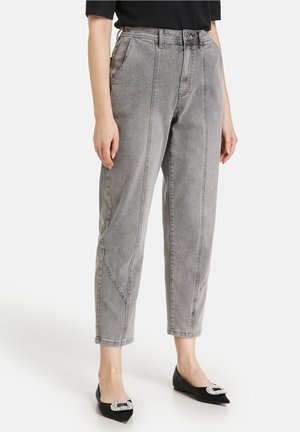 Person wearing high-waist gray tapered jeans with front seams, paired with black pointed flats featuring large rhinestone buckles.