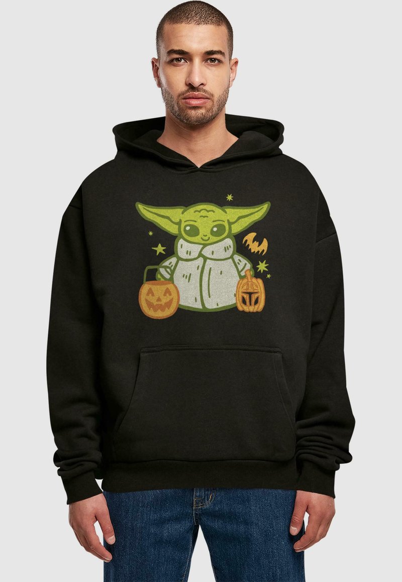 Svart hoodie med en grön tecknad karaktär med stora öron som håller i pumpa-bucketar, mot en enkel bakgrund.