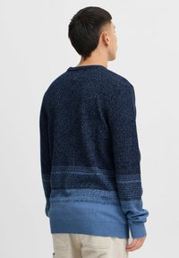 Marineblå og lyseblå strikkegenser med teksturert mønster og ribbestrikkede mansjetter. Lange ermer og rund halslinning, med en gradientdesign.