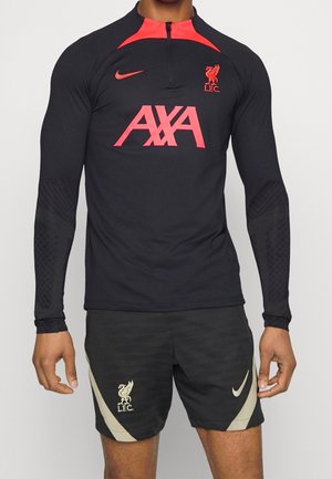 Zwart sportshirt met lange mouwen en rode accenten, met het "AXA" logo en het embleem van Liverpool FC. Gecombineerd met zwarte shorts en Nike branding.