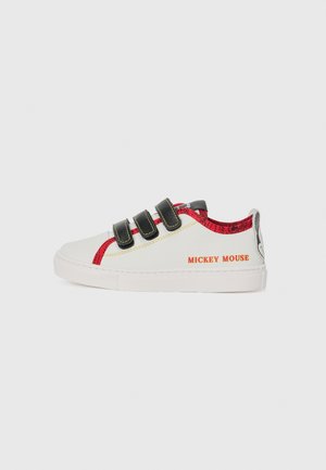 Zapatilla blanca con detalles rojos, correas de velcro negras y costuras amarillas. Presenta "MICKEY MOUSE" impreso en naranja en el lateral.