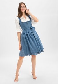 Blue traditional dress with a fitted bodice, ruffled neckline, and a flared skirt. Features a satin tie at the waist and textured patterns.