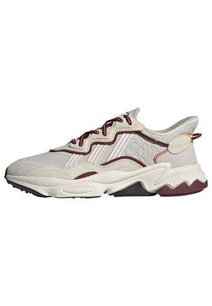 Baskets blanches et bordeaux avec panneau latéral texturé, design ondulé, semelle épaisse et lacets avec accents bordeaux, vues du côté extérieur.