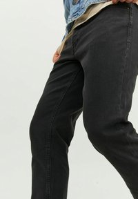 Svarta jeans i denim med smal passform, utrustade med subtila sömmar, en klassisk design med fem fickor och en slät textur.