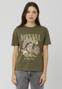 T-shirt en coton vert olive avec un design graphique floral et le texte "NIRVANA" ainsi que "Heart-Shaped Box" en accents blancs et dorés.