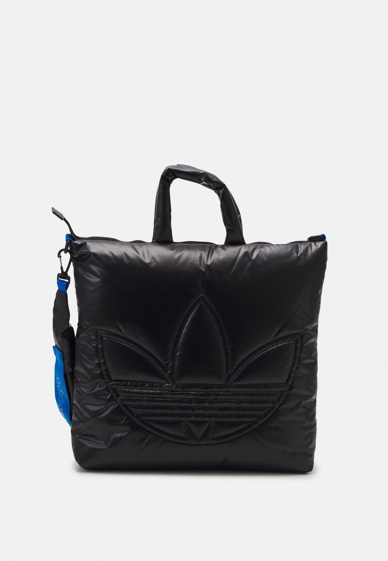 Sac noir matelassé avec un logo Adidas texturé, deux poignées courtes et une sangle bleue. Comprend une fermeture éclair et une finition lisse et brillante.