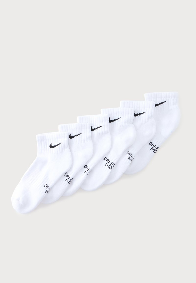 Sept paires de chaussettes de cheville Nike blanches avec logos swoosh noirs et texte "DRI-FIT", disposées en rangée diagonale sur un fond clair.