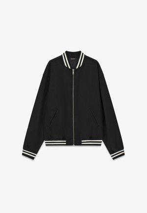 Zwarte bomberjack met een ritssluiting aan de voorkant, zijzakken en geribbelde kraag en manchetten met strepen in wit en donkergrijs. Gladde, lichtgewicht stof.