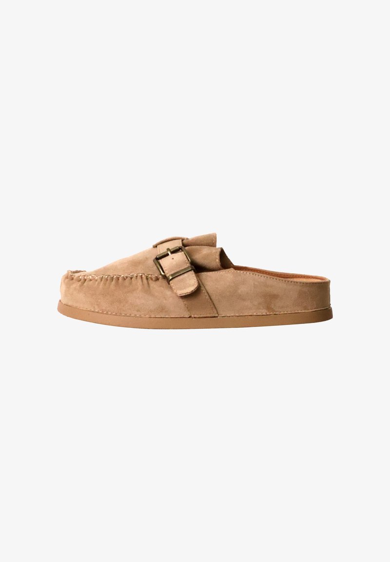 Mocassins en daim couleur tan à enfiler avec boucle latérale et semelle plate basse, sans talon pour un port facile.