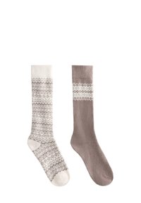 Dve dlhé ponožky vedľa seba; ľavá ponožka je biela s hnedým geometrickým vzorom, pravá ponožka je hnedá s bielym geometrickým pásom blízko vrchu.