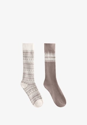 Dva duga čarapa jedno pored druge; lijeva čarapa je bijela s smeđim geometrijskim uzorkom, desna čarapa je smeđa s bijelom geometrijskom trakom blizu vrha.