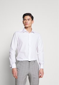 Witte lange mouw shirt met een klassieke kraag, gecombineerd met grijze geruite broeken. Slanke pasvorm met knoopmanschetten en een gladde textuur.