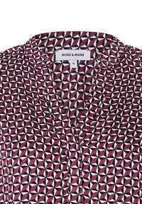 Blouse avec col présentant un motif géométrique en maroon, blanc et noir. Tissu léger avec une texture lisse. Étiquette de marque visible.