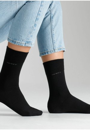 Fekete bokazokni puha anyagból, bordás felső szélekkel, és egy kis címkével, amelyen szürkével "CA-SOFT" felirat található.