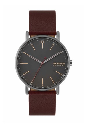 Minimalistisch Skagen polshorloge met donkergrijze wijzerplaat, gouden uurmarkeringen, rode secondenwijzer, zilveren kast en bruine leren band.