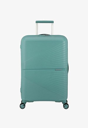 Valigia rigida turchese con un design a strisce diagonali testurizzate, manico telescopico e quattro ruote girevoli per la mobilità.