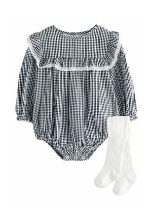 Salopette pour bébé à carreaux bleu marine et blanc avec un col volanté et une bordure en dentelle, accompagnée de chaussettes blanches à côtes.