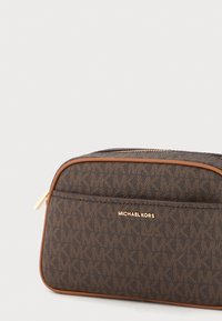 pruun monogramm kangast kosmeetikatkaan, millel on kuldne tõmblukk, beežid aktsendid ja ristkülikuline kuju, millel on nimi "Michael Kors" kullatud fondis.
