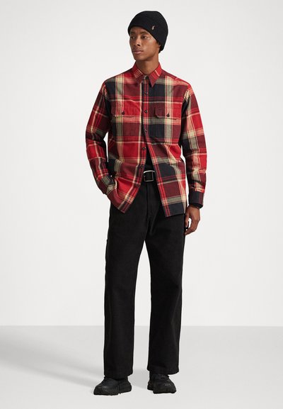 Red plaid shirt with black and yellow accents, button-down collar, two chest pockets, paired with black pants and black shoes.