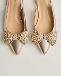 Ballerine a punta in tessuto metallico oro, con un grande fiocco gioiello sulla parte anteriore decorato con cristalli oro e trasparenti.