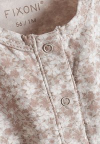 Bluse für Säuglinge in Hellbraun mit floralem Muster, aus weichem Stoff, mit rundem Halsausschnitt und zwei Knöpfen mit Metallösen.