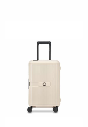 Maleta rígida color crema con cuatro ruedas, nervaduras verticales, asa telescópica negra y cerradura central incorporada.